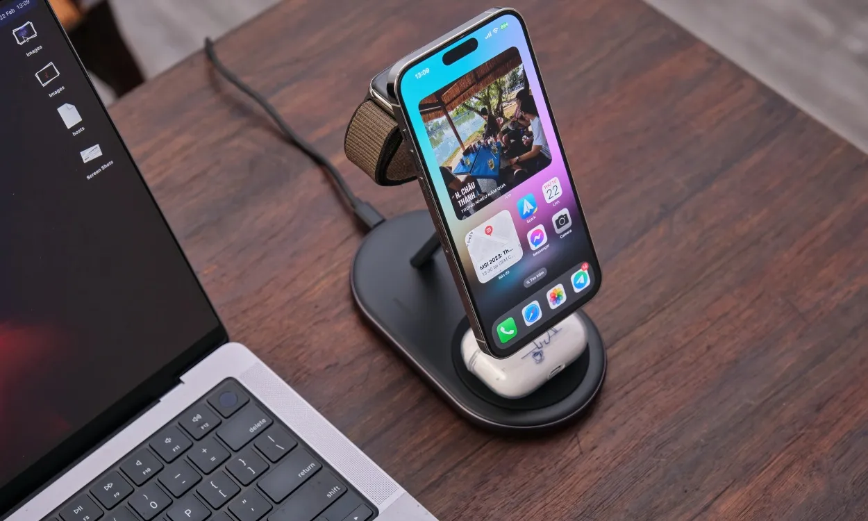 صورة لهاتف iPhone موضوع على شاحن MagSafe عمودي مع Apple AirPods