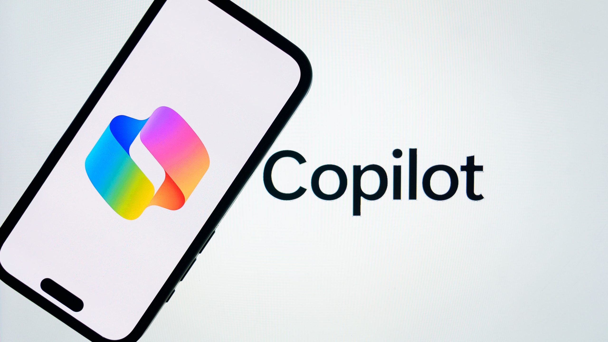 In this photo illustration, 'Microsoft Copilot' logo is displayed on mobile phone screen in front of a screen displaying the inscription of 'Copilot' in Ankara, Turkiye on March 14, 2025.