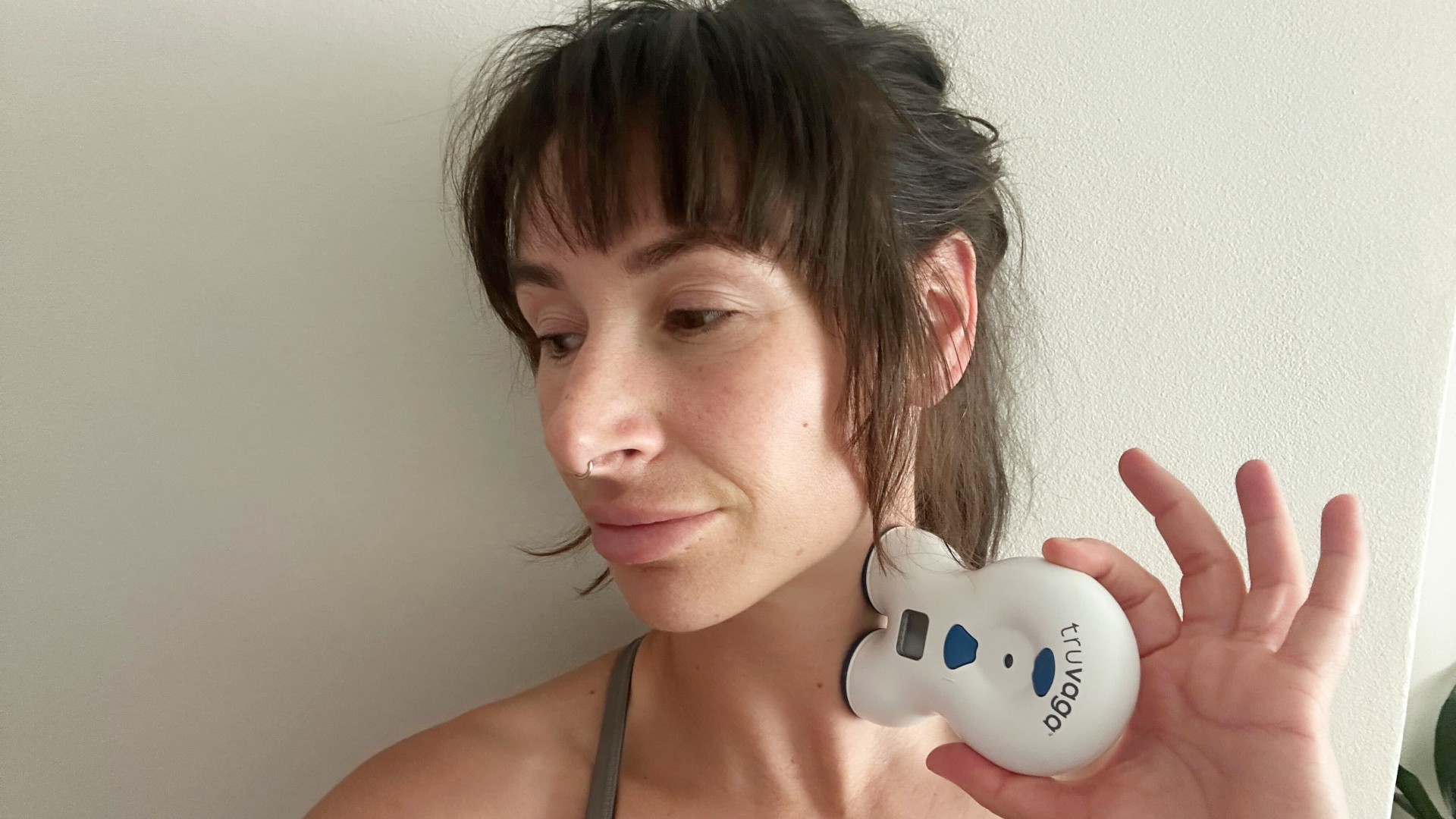 Sam (tester) holding Truvaga vagus nerve stimulator to her neck