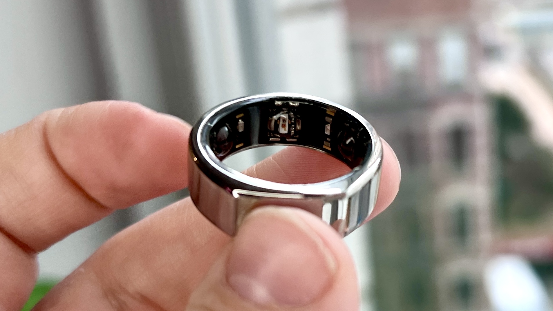 Oura Ring Generation 3 in silver held between a person's fingers
