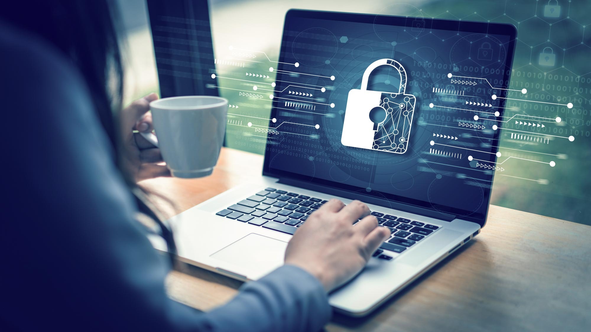 امرأة تستخدم جهاز الكمبيوتر المحمول الخاص بها بأمان مع فنجان قهوة في متناول اليد