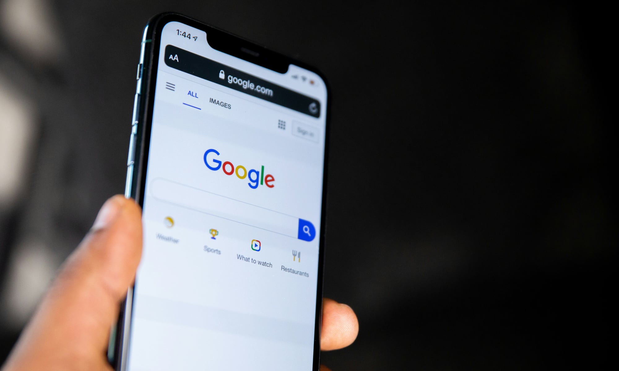 Person holding iPhone with Google search page