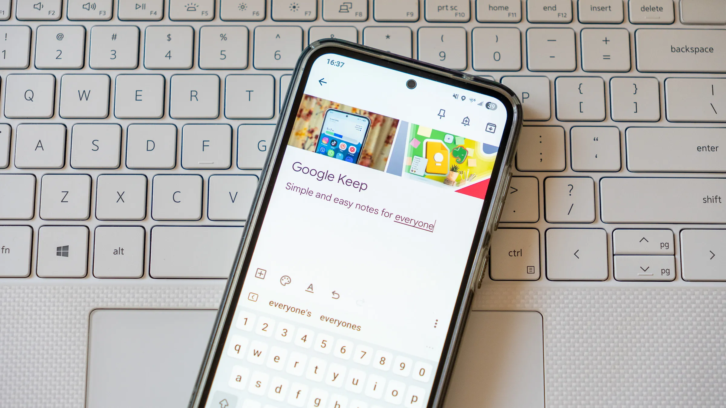 ملاحظة Google Keep معروضة على هاتف موضوع على لوحة مفاتيح كمبيوتر محمول