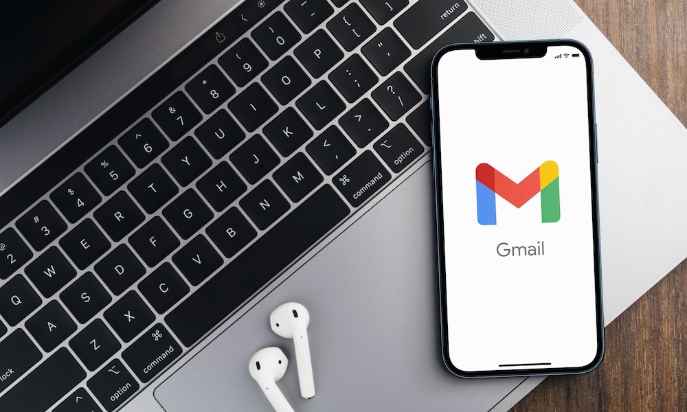 تطبيق Gmail على شاشة الهاتف الذكي على خلفية خشبية مع جهاز كمبيوتر بجانبه. منظر علوي. ريو دي جانيرو ، ريو دي جانيرو ، البرازيل. أغسطس 2021.