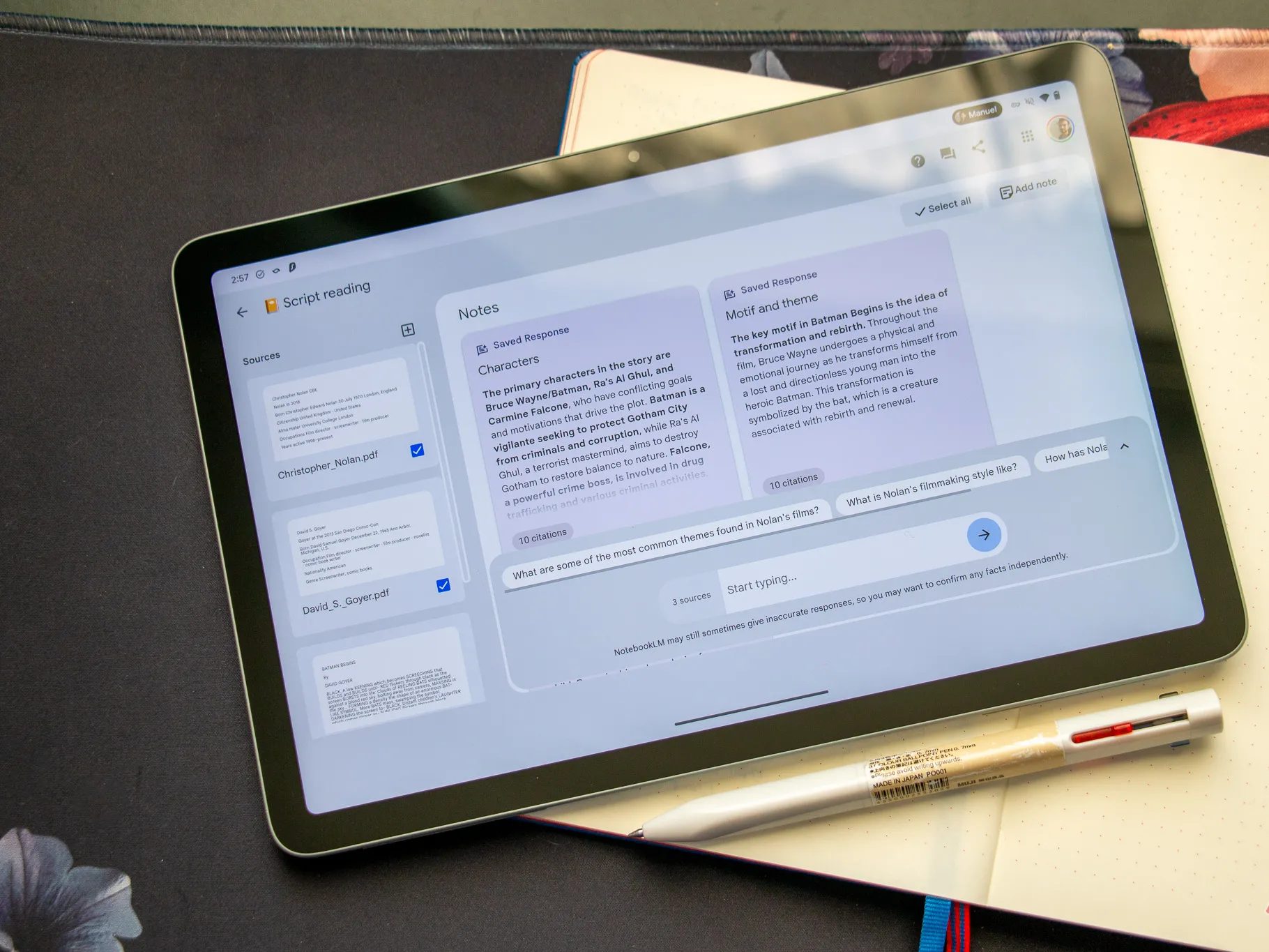 جهاز لوحي يعرض موقع NotebookLM مفتوحًا، موضوعًا على طاولة مع دفتر ملاحظات ورقي أسفله