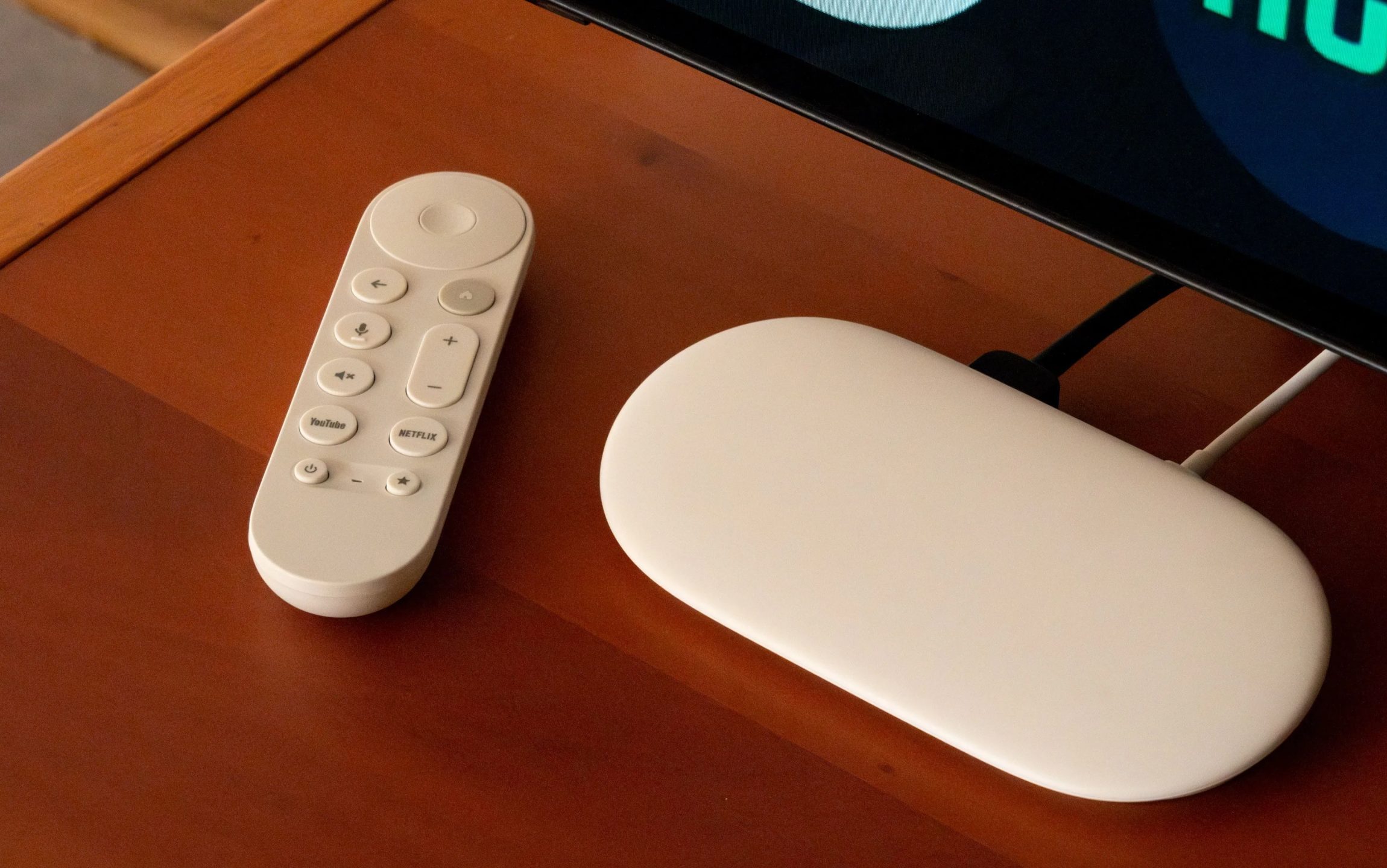 جهاز Google TV Streamer بجوار تلفزيون وجهاز تحكم عن بعد