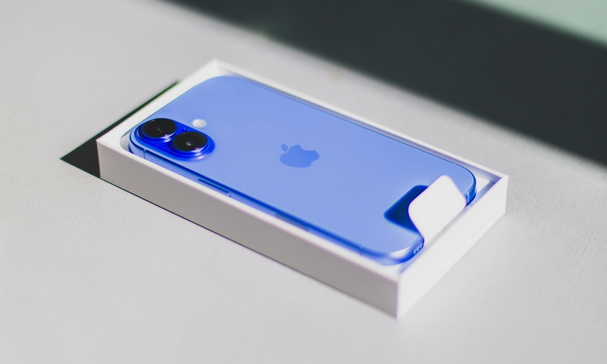 iPhone 16 in open box on table iPhone 16 in open box on table