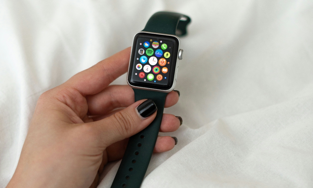 person holding Apple Watch over bed sheets person holding Apple Watch over bed sheets
