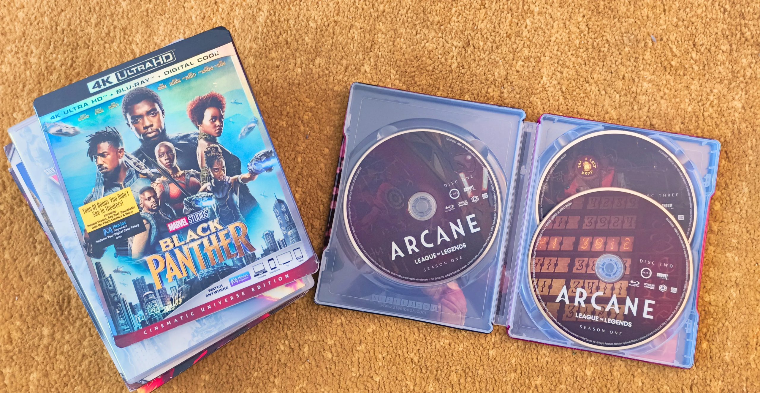 نسخة خاصة من الموسم الأول من مسلسل Arcane على Blu-Ray مفتوحة بجوار مجموعة من أقراص DVD و Blu-Ray