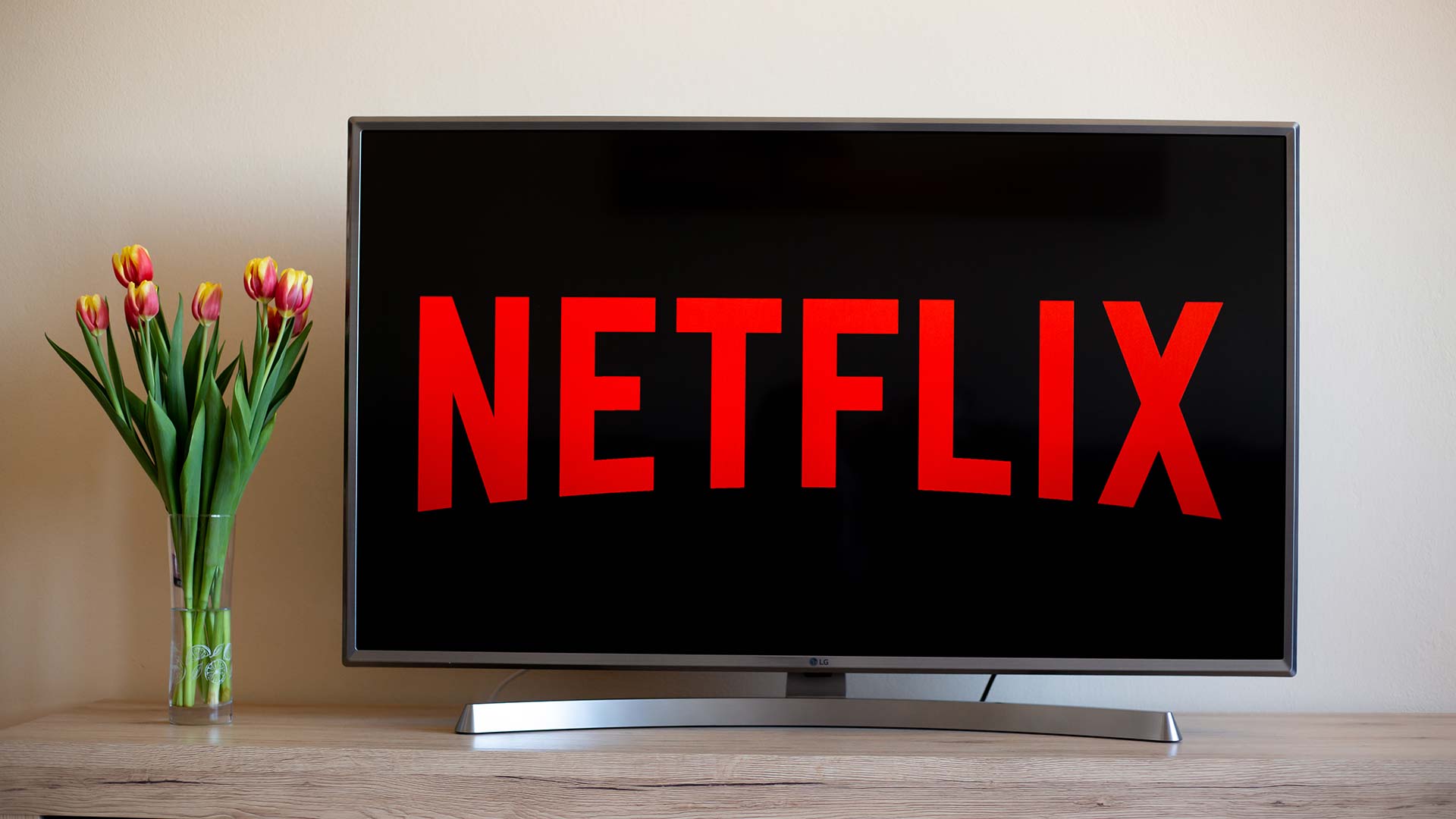 شعار Netflix على شاشة تلفزيون بجانب مزهرية زهور