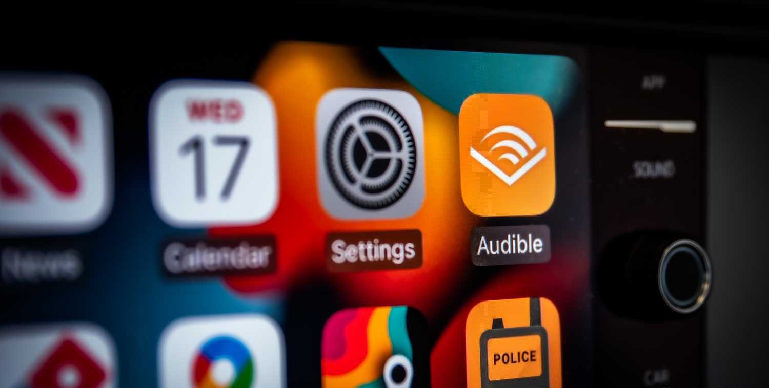 صورة ثابتة لشاشة Apple CarPlay مع تطبيق Audible في المقدمة.