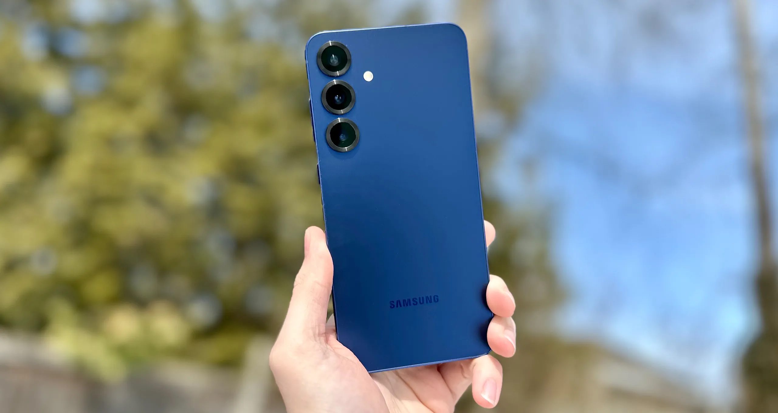 Samsung Galaxy S25+ in-hand outside with trees in the background