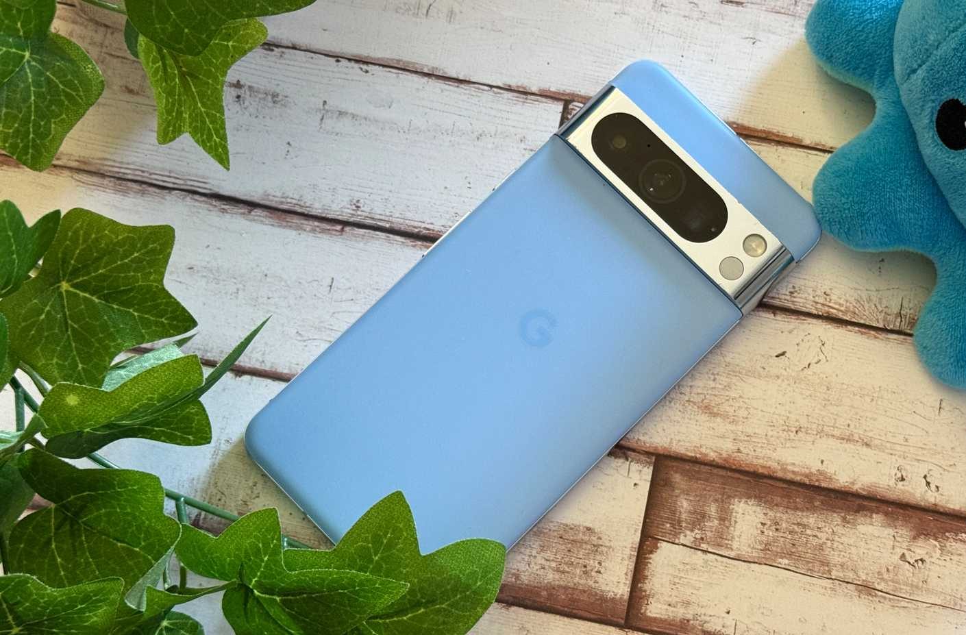 Google Pixel 8 Pro laying next to a fake plant and a plushie