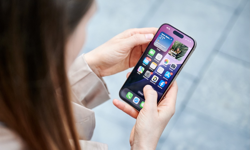 Lviv, Ukraine October 10, 2024: close up person interacts with smartphone Iphone 16 Pro, navigating home screen filled with apps and widgets, showcasing sleek user interface, personalized features.