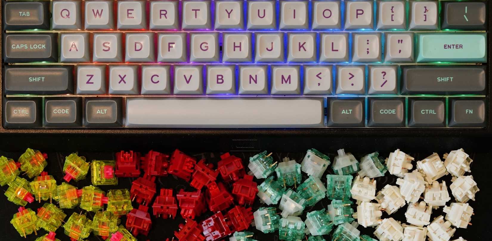 أربعة أنواع ملونة من مفاتيح لوحة المفاتيح الميكانيكية موضوعة تحت لوحة مفاتيح رمادية