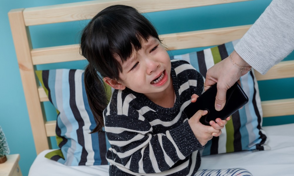 أم تمسك هاتفًا وطفل يبكي. لا تستخدم الهاتف الذكي