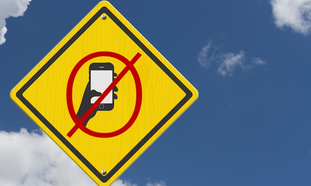 رمز ممنوع إرسال الرسائل النصية أو استخدام الهاتف الخلوي أثناء القيادة على لافتة طريق تحذيرية