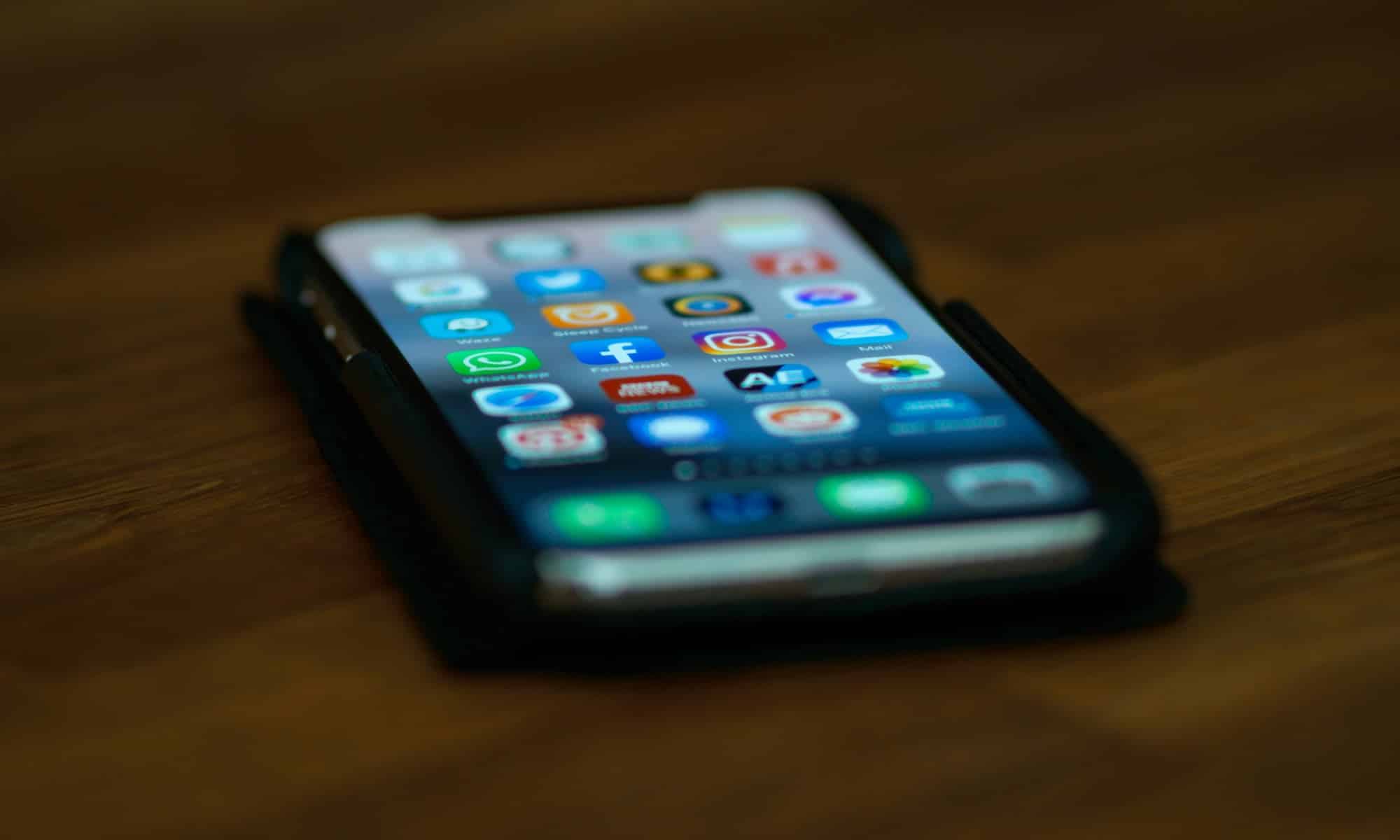 iPhone on table with apps home screen blurred