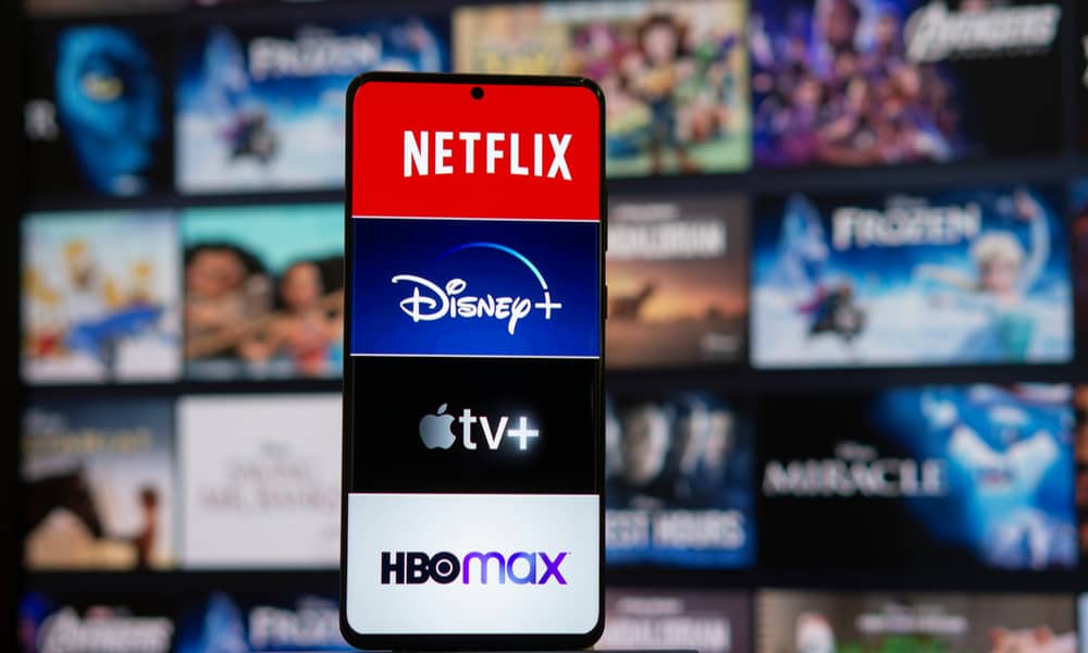 هاتف يعرض شعارات Netflix و Disney Plus و Apple TV Plus و HBO Max مع عروض في الخلفية