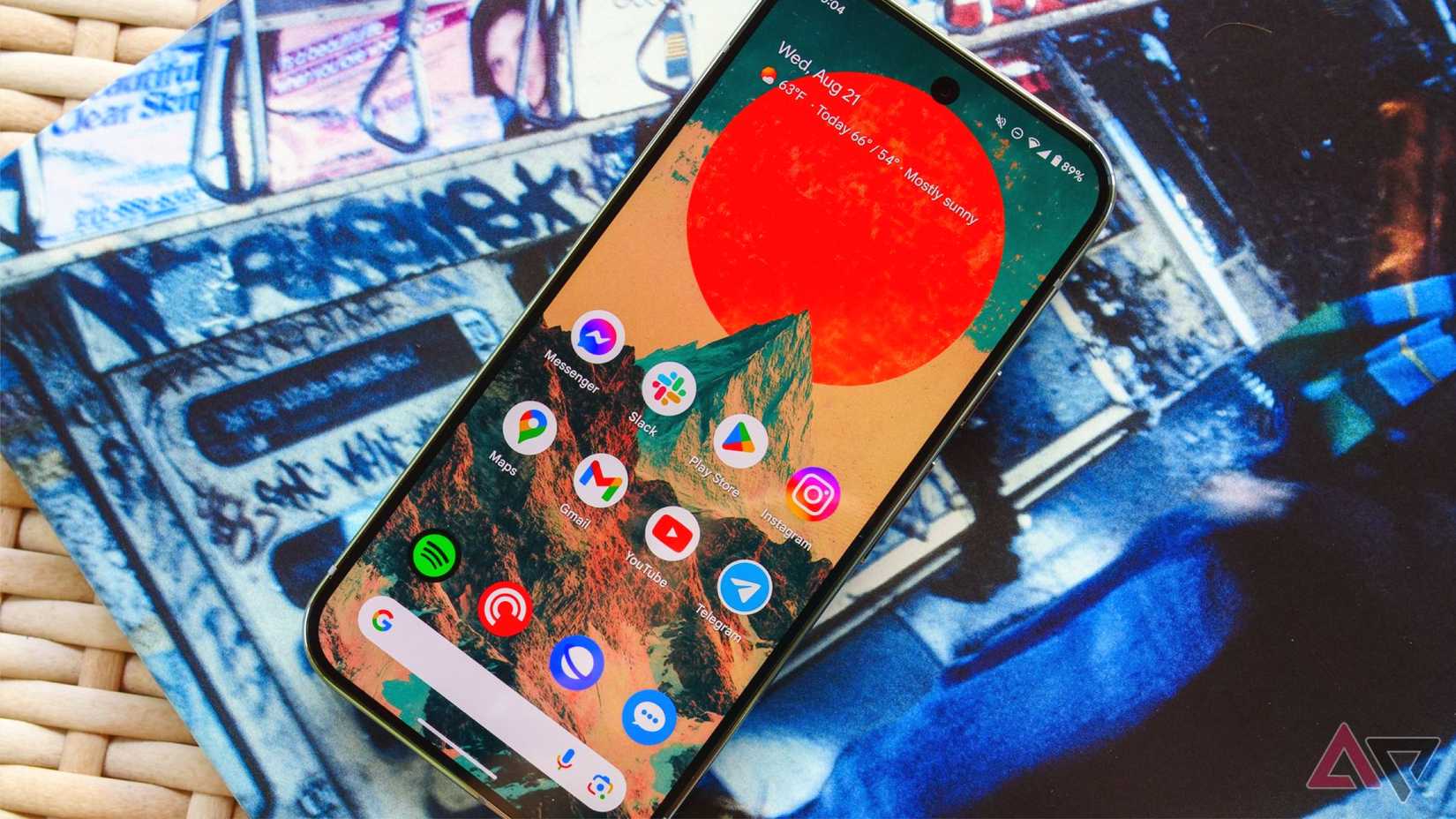 جهاز Pixel 9 Pro على طاولة من الخيزران وموضوع فوق غلاف ألبوم مع تشغيل الشاشة
