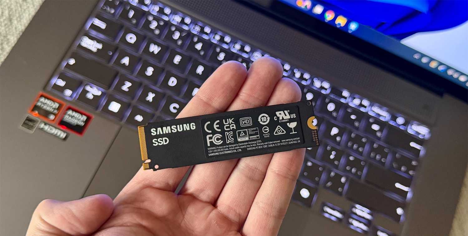 شخص يحمل قرص SSD داخلي أمام جهاز كمبيوتر محمول.