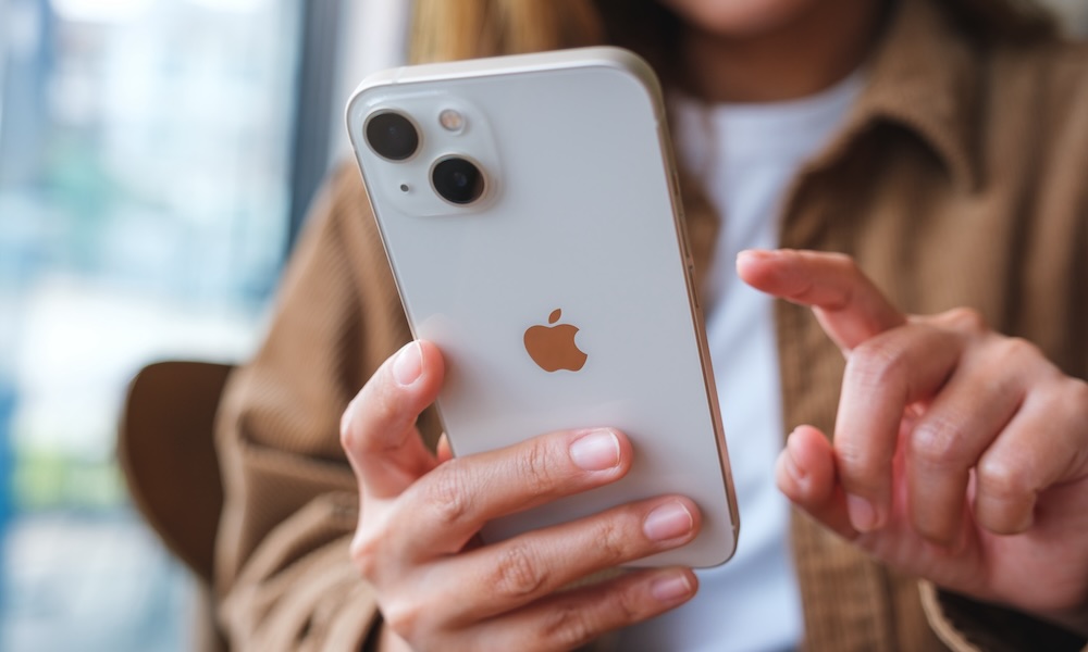 امرأة تمسك وتلمس شاشة هاتف iPhone 13 في شيانغ ماي، تايلاند