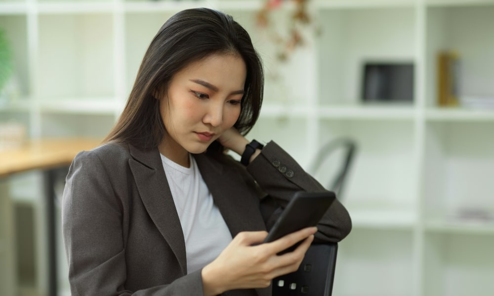 امرأة تنظر إلى جهاز iPhone بتعبير قلق