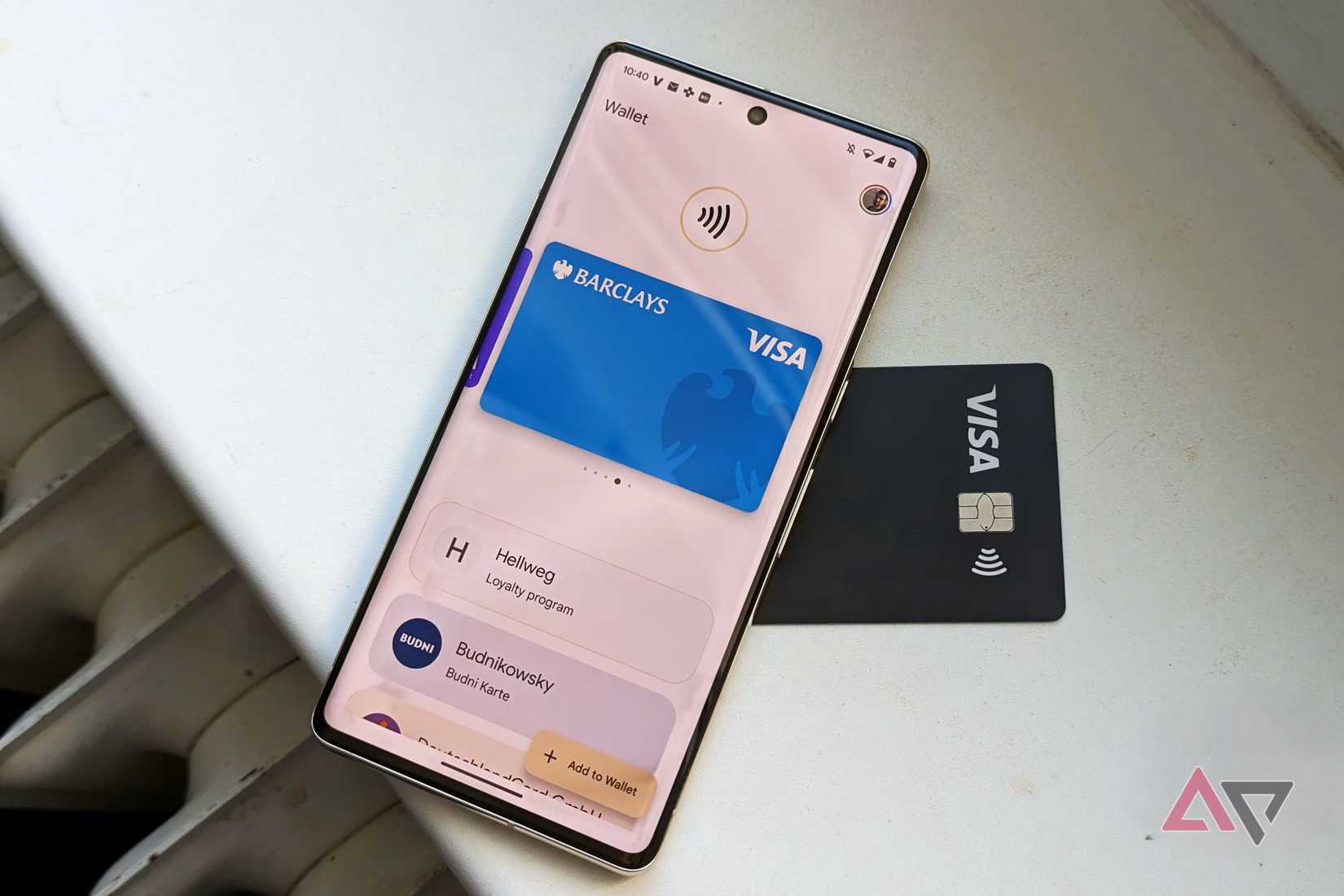 Google Wallet مفتوح على هاتف Google Pixel موضوع فوق بطاقة Visa سوداء.