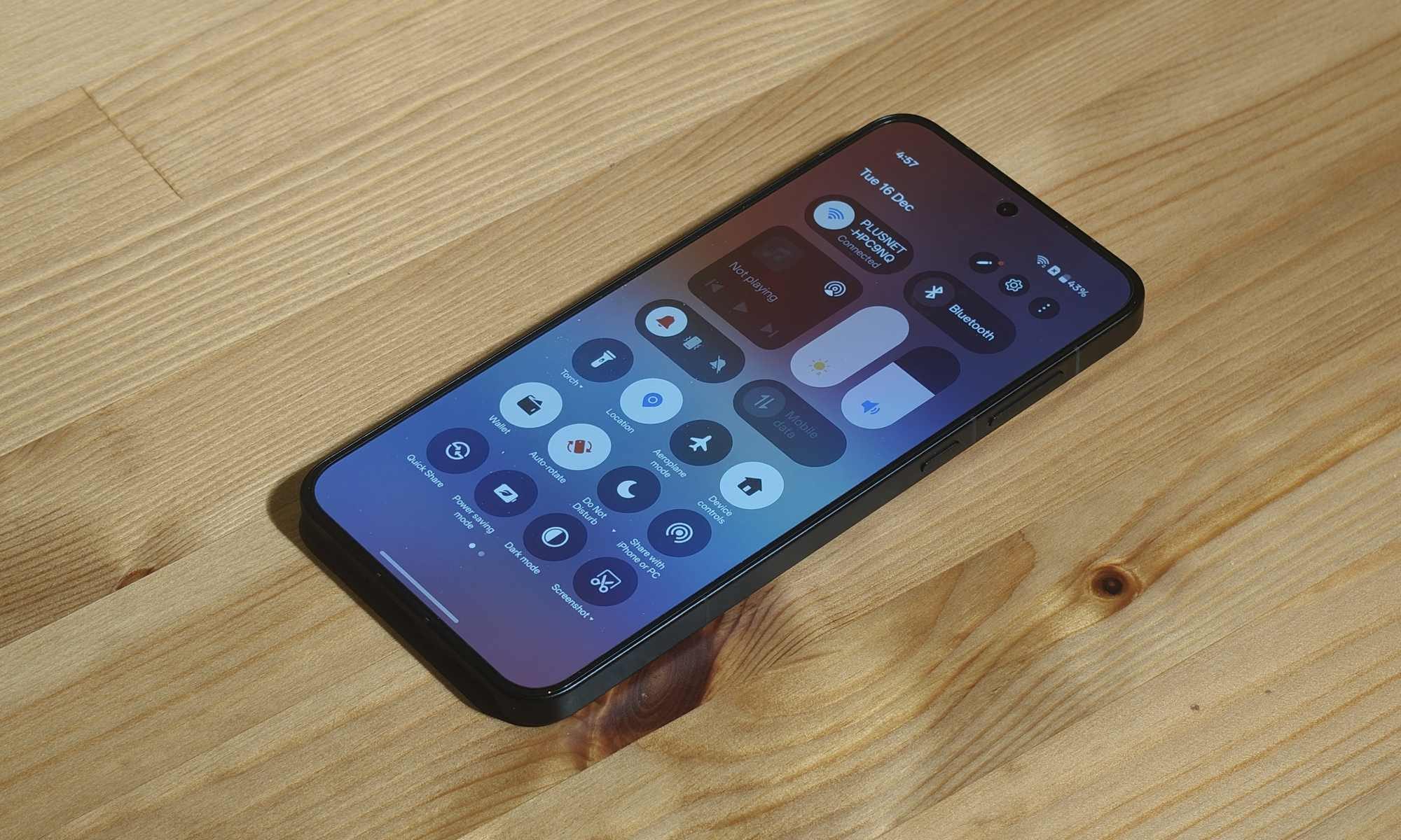 قائمة الإعدادات السريعة في OnePlus 15R، بينما هي مسطحة على طاولة خشبية.