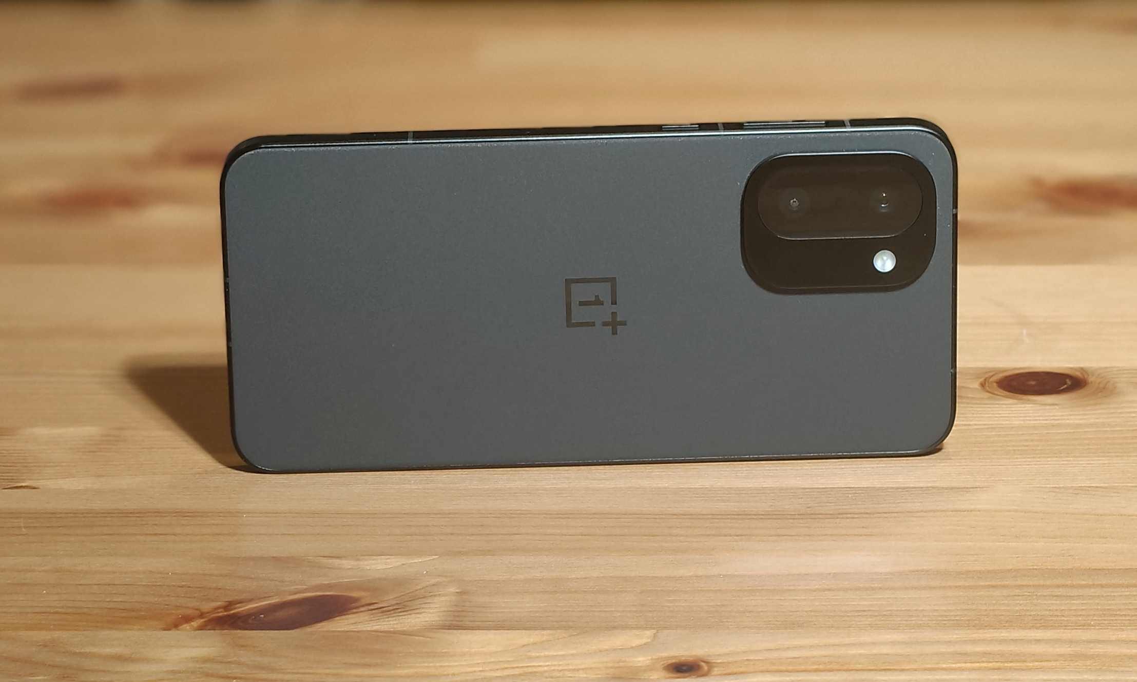 الجزء الخلفي من OnePlus 15R، أفقيًا على طاولة خشبية.