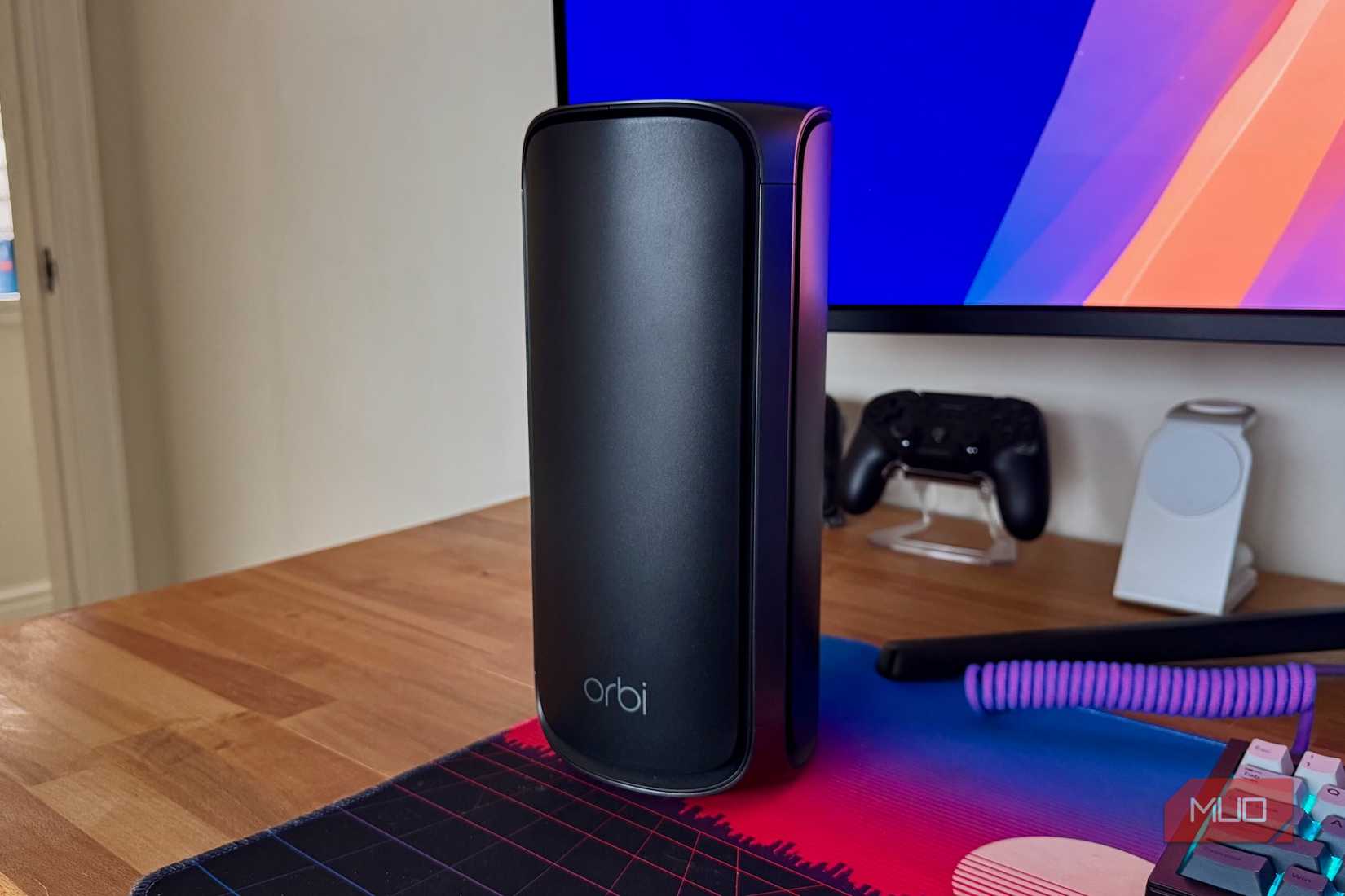 جهاز توجيه Netgear Orbi باللون الأسود على مكتب خشبي