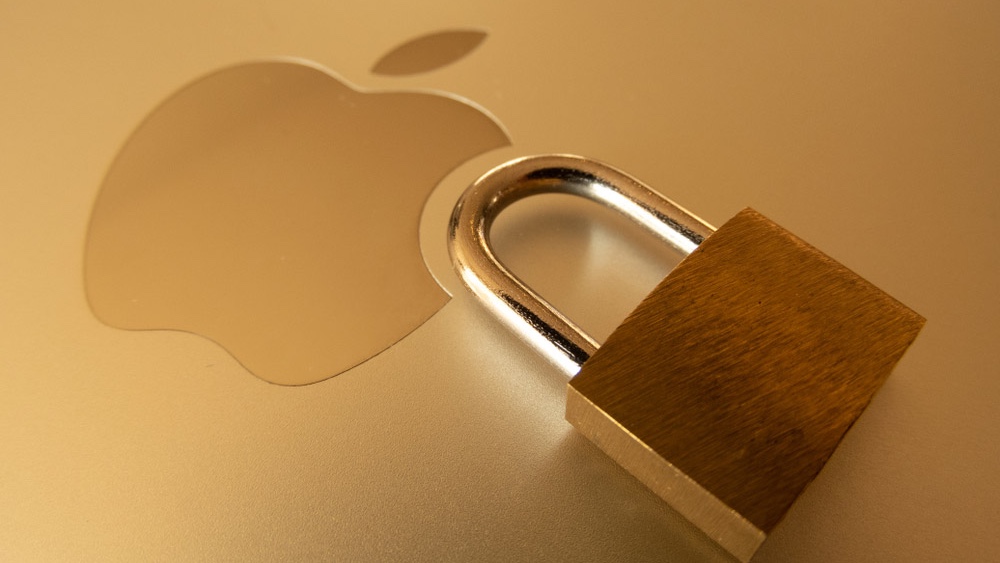قفل بجوار شعار Apple على غطاء حاسوب Apple محمول ذهبي اللون.