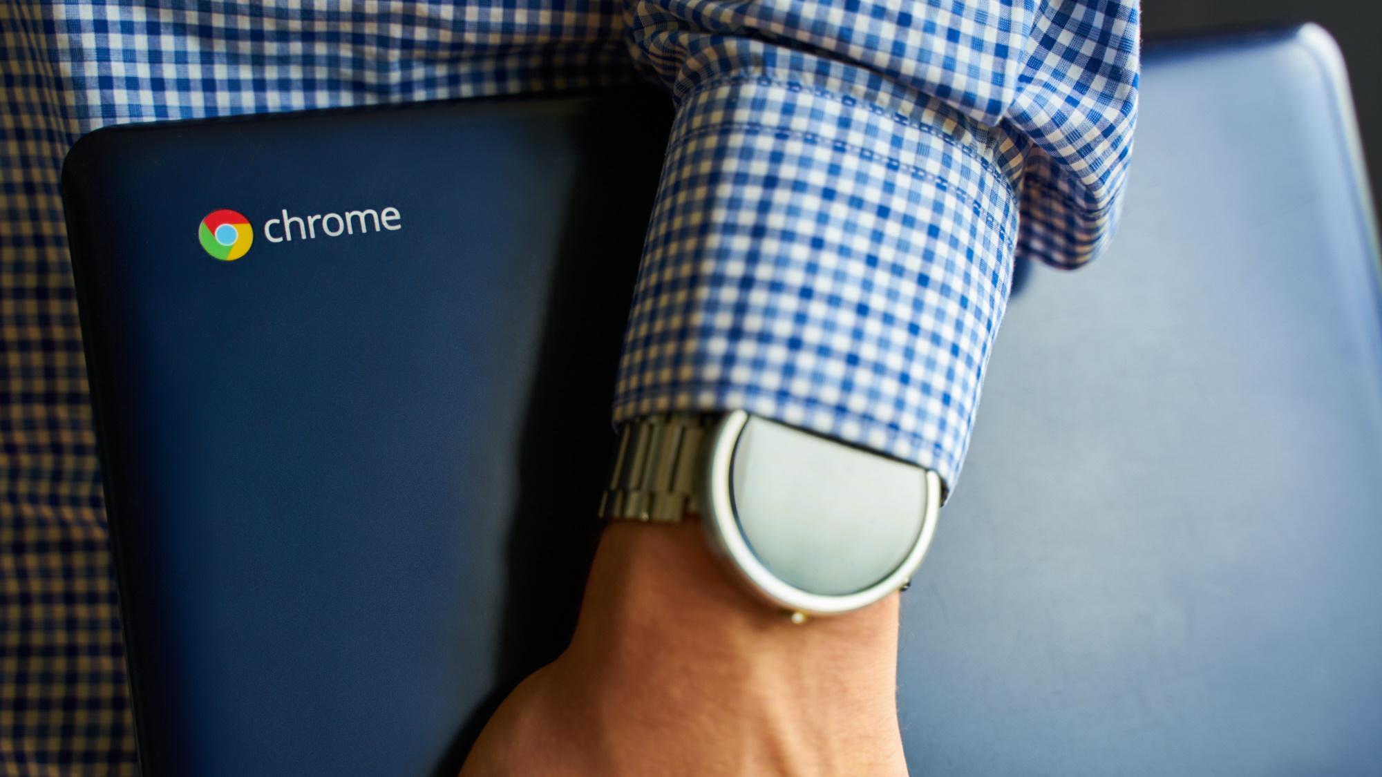 رجل يحمل جهاز Chromebook بجانبه مع ساعة ذكية ظاهرة على معصمه