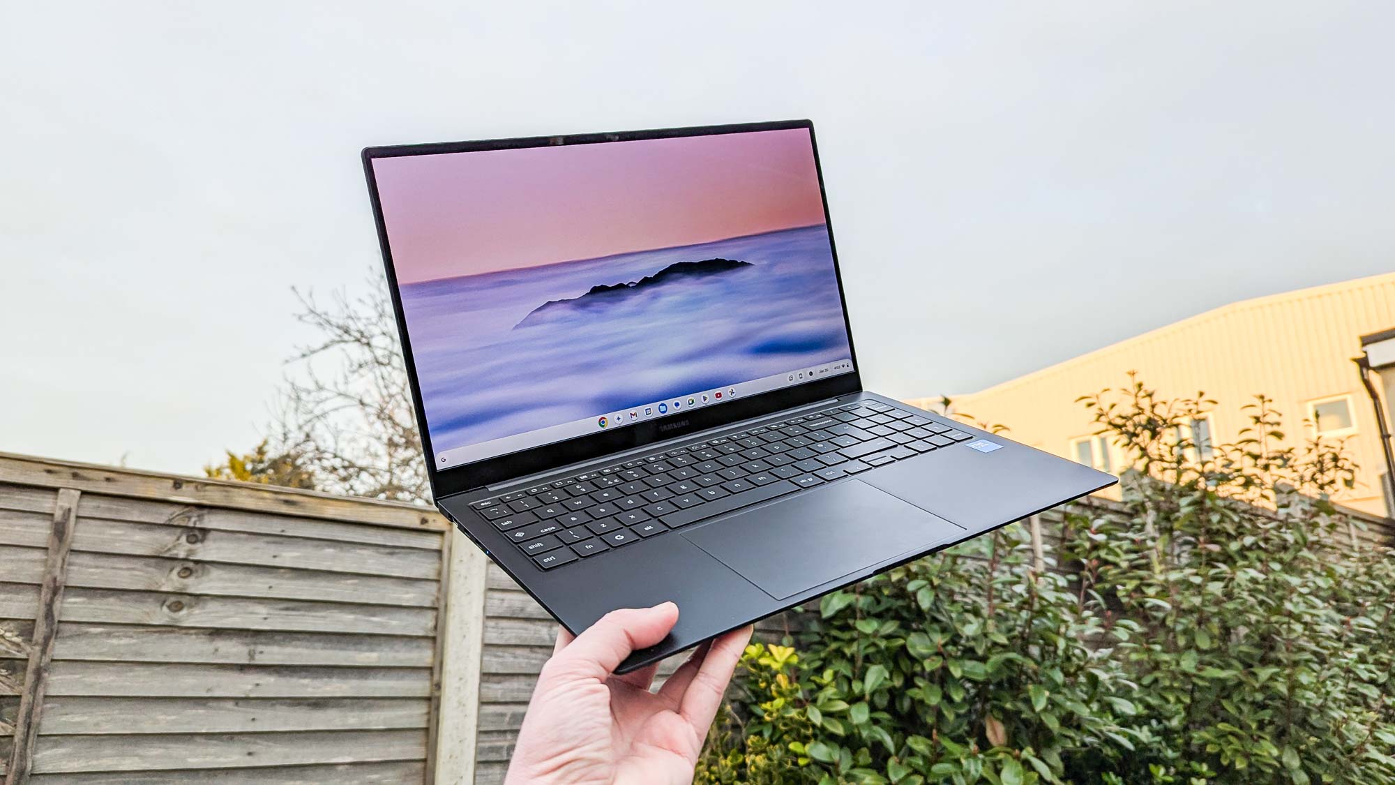 جهاز Samsung Galaxy Chromebook Plus محمول باليد ومرفوع نحو السماء