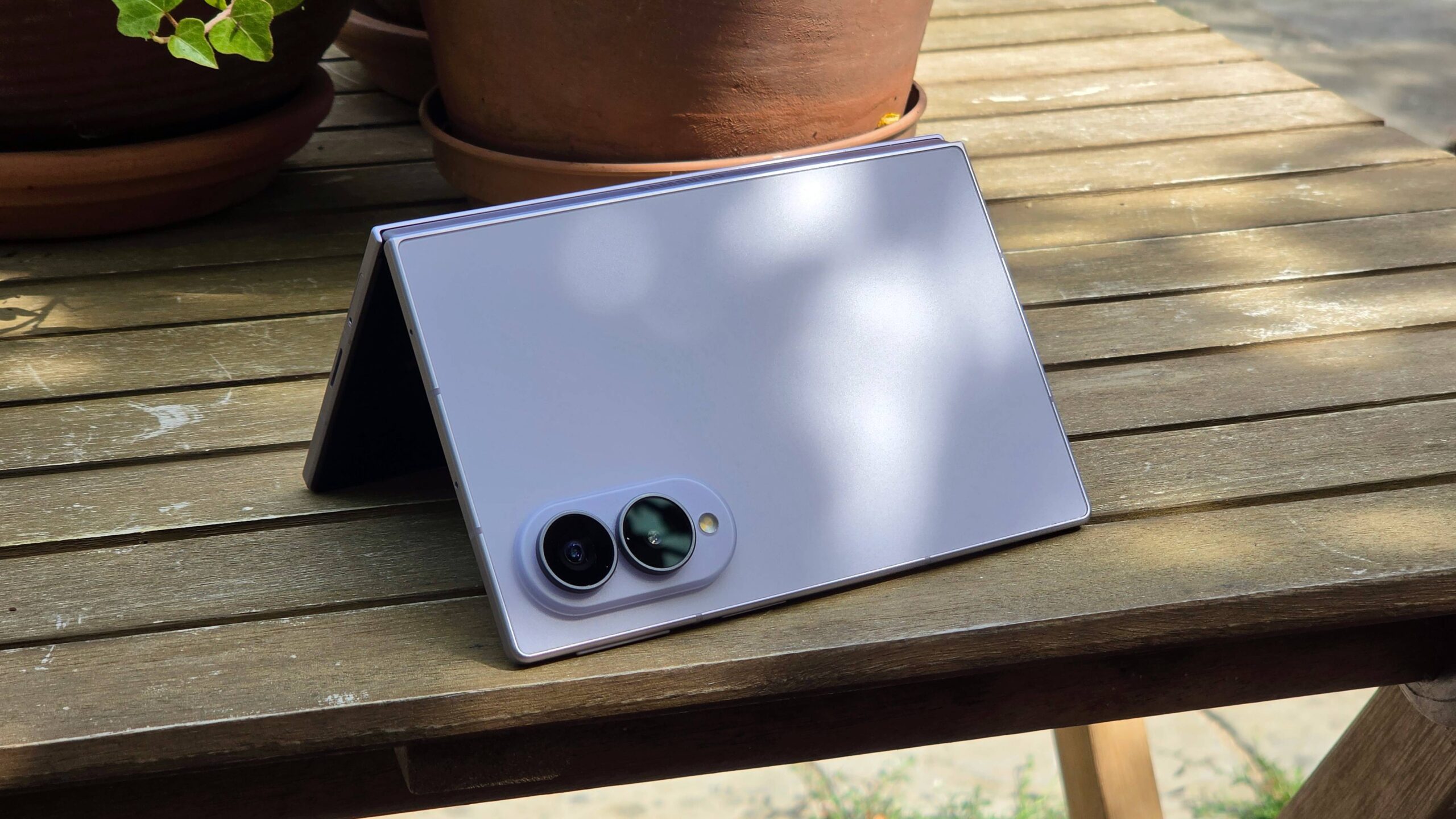 هاتف Samsung Galaxy Z Fold 8 على طاولة خشبية، على شكل حرف 'V' مقلوب.