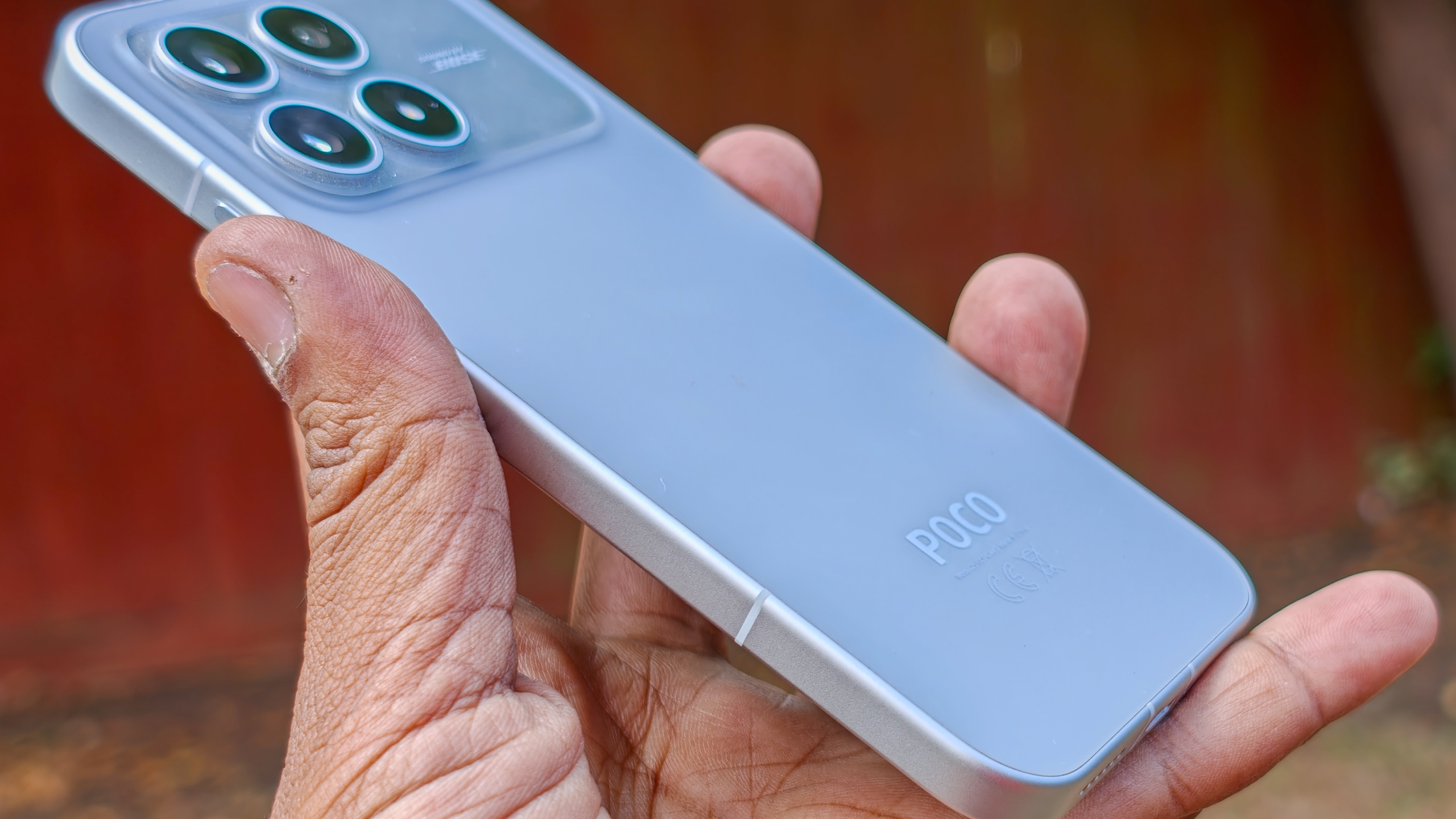 هاتف Poco F8 Pro باللون الفضي في اليد بخلفية حديقة