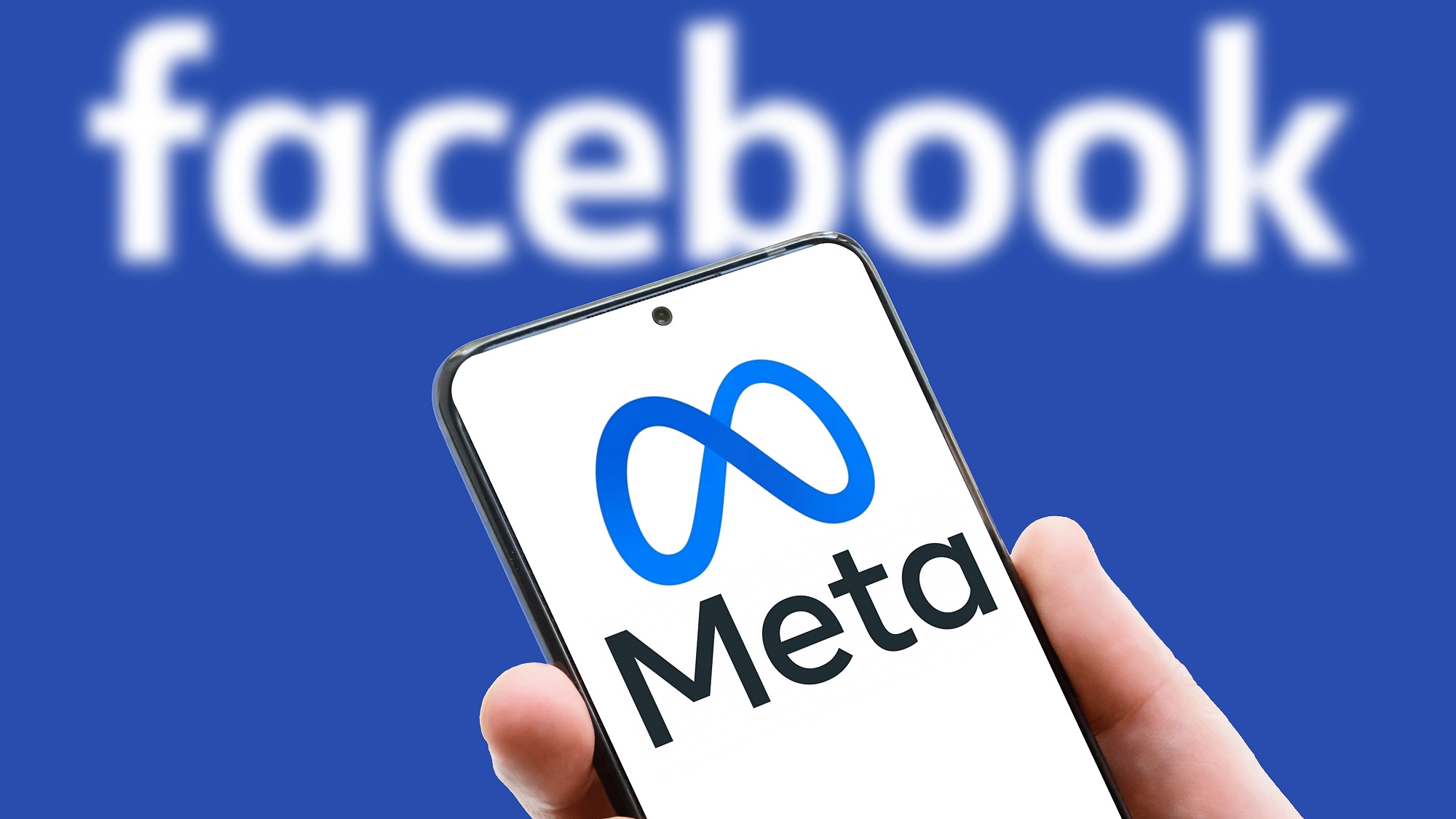 شعار Meta على شاشة هاتف محمول بخلفية كلمة Facebook. Facebook بعد إعادة تسميته وتغيير اسمه إلى Meta.