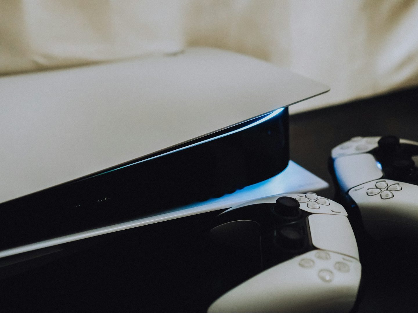 جهاز PS5 موضوع على جانبه مع وحدتي تحكم DualSense بجانبه على اليمين.