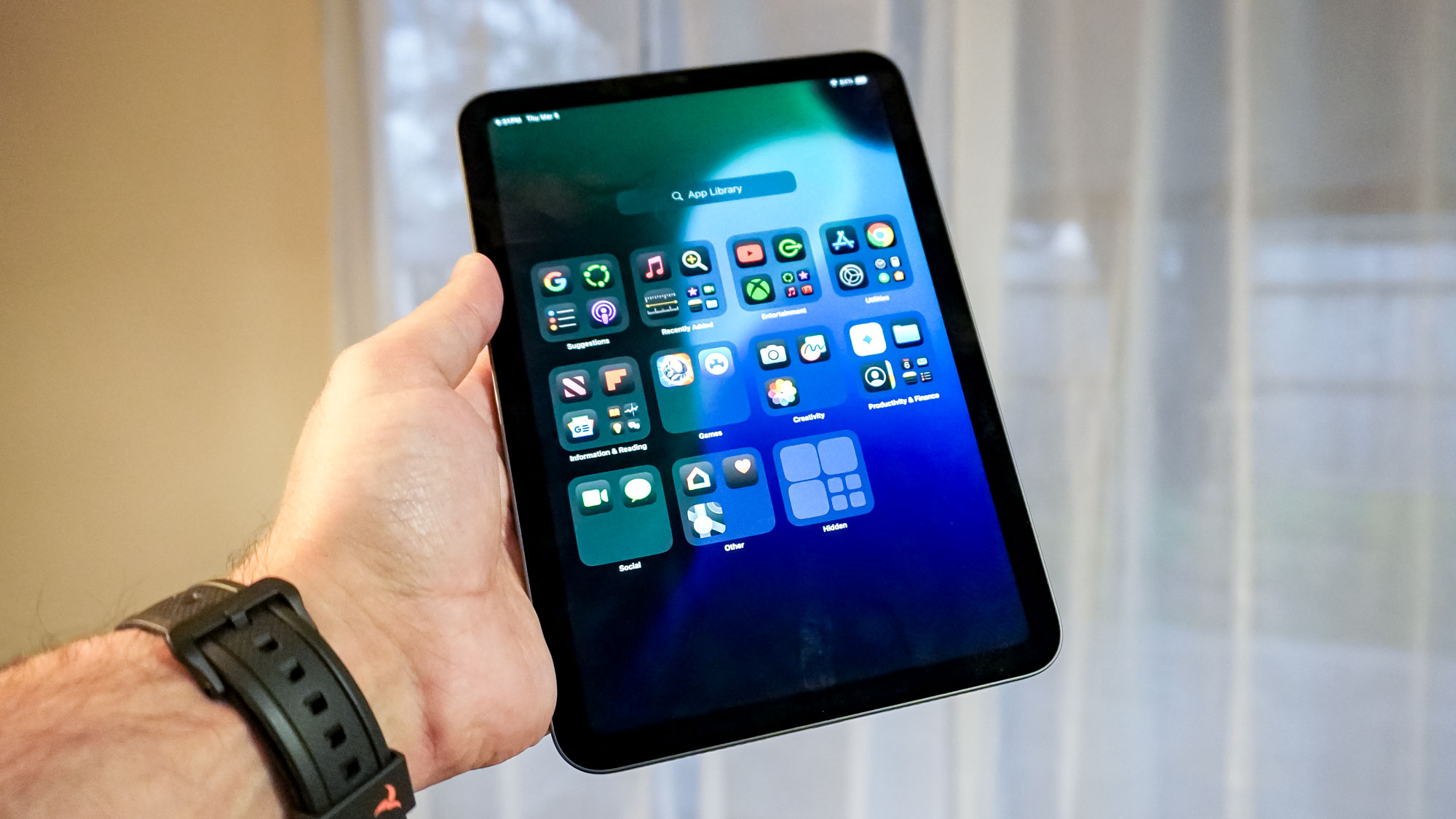 جهاز iPad mini 7 محمول باليد أمام باب زجاجي منزلق