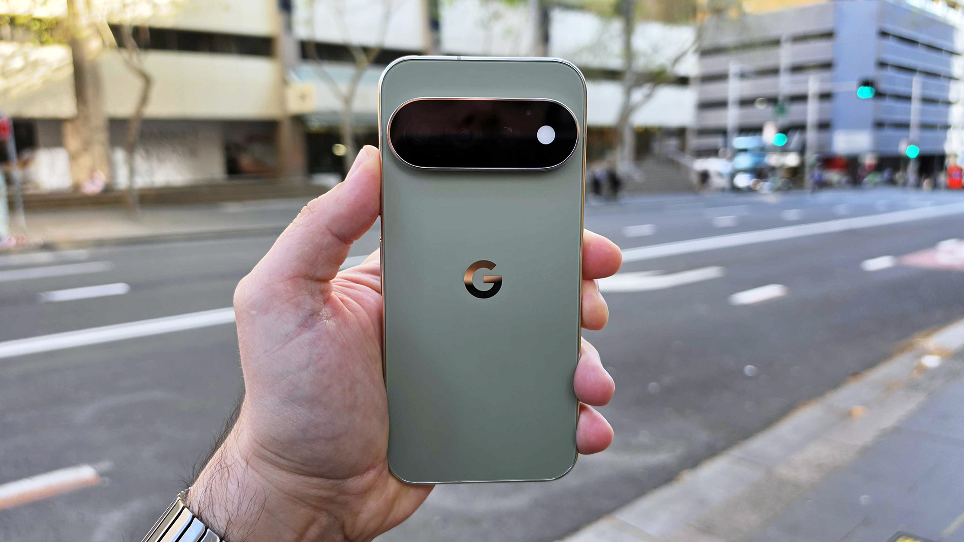صورة لهاتف Google Pixel 11 Pro في اليد بخلفية شارع أثناء النهار