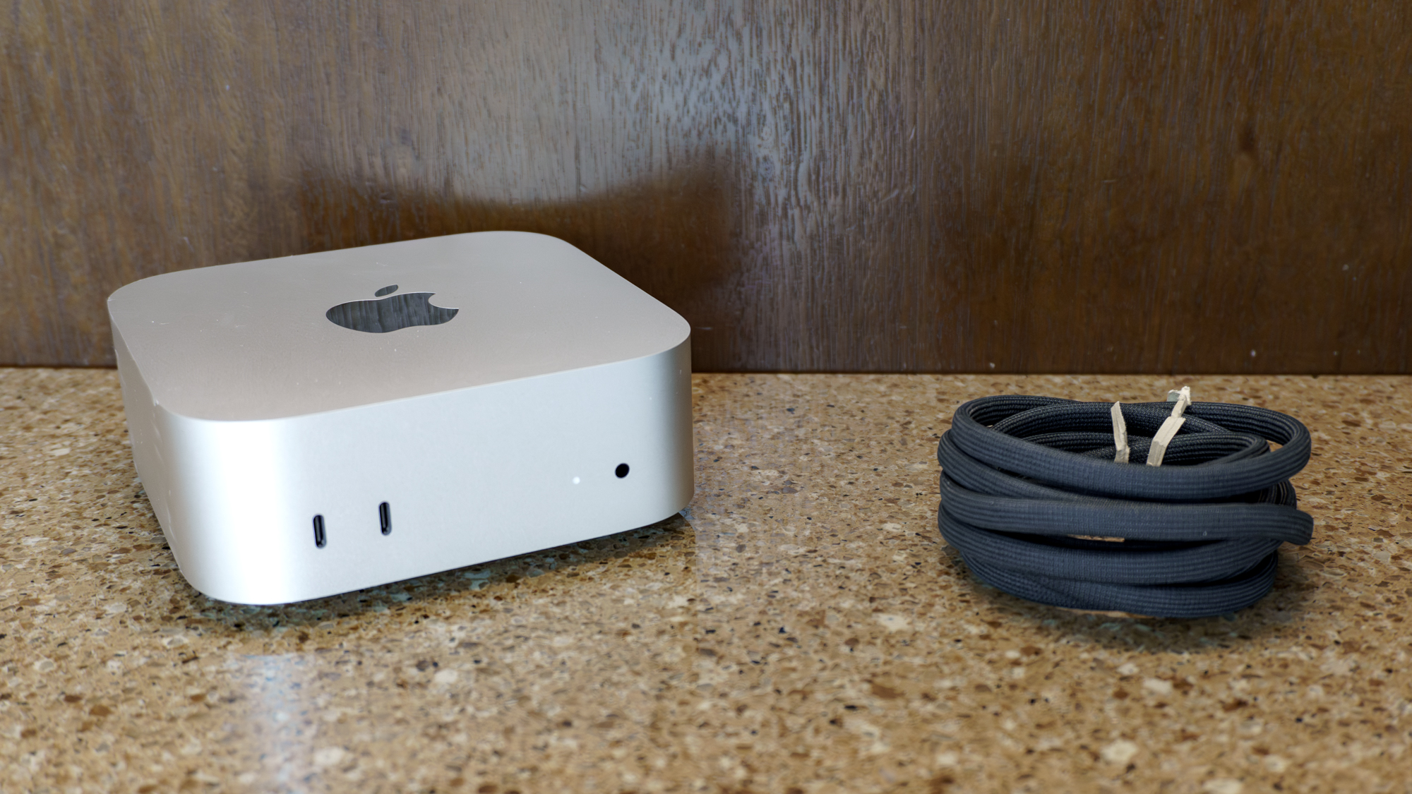 جهاز Mac mini M6 غير معلب على طاولة مع سلك الطاقة بجانبه