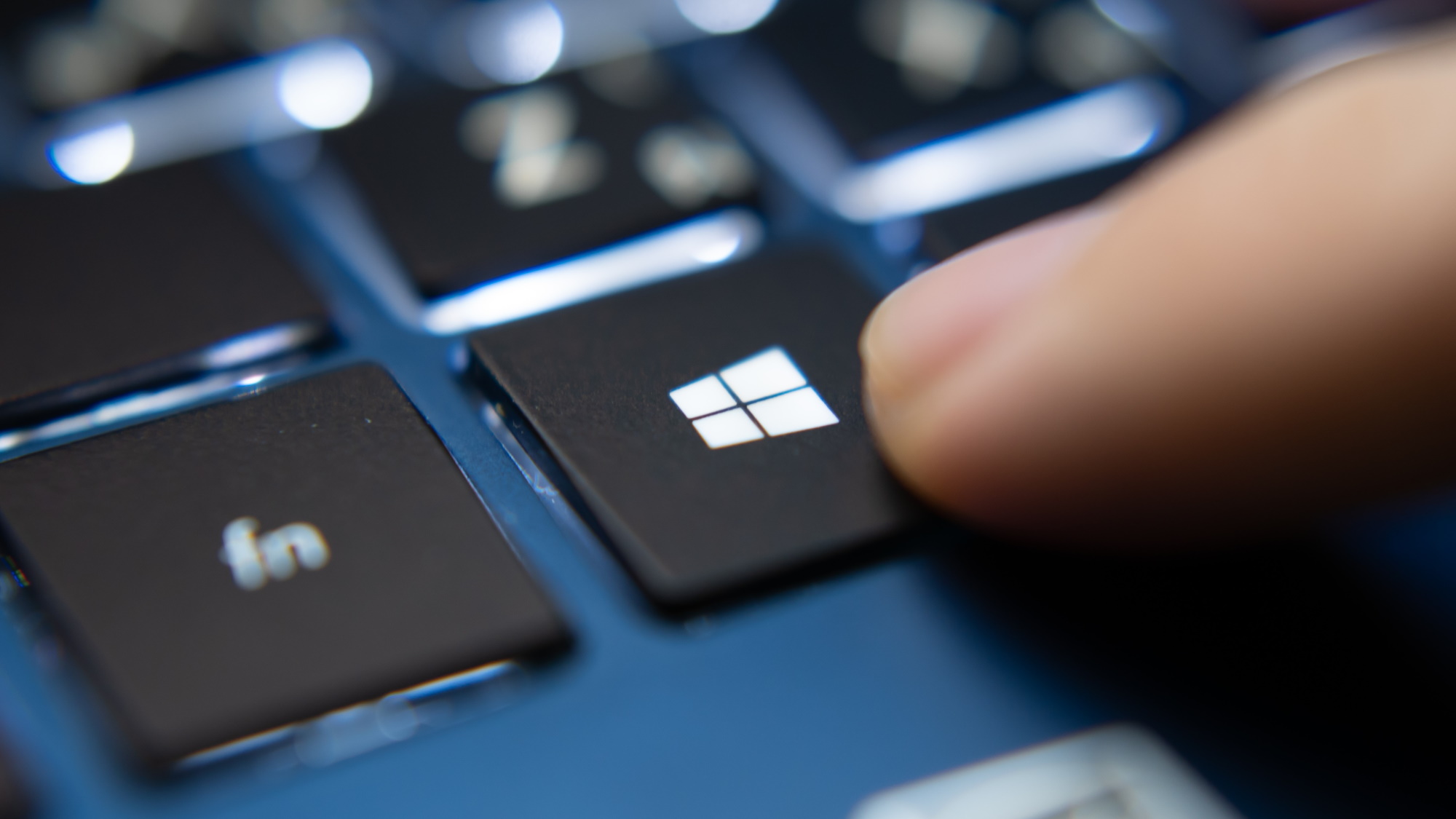 Un dedo pulsando una tecla del teclado con el logotipo de Windows.