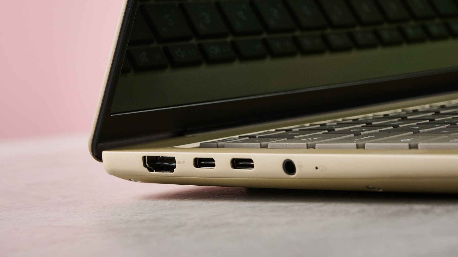 لقطة مقربة للمنافذ على الجانب الأيسر من جهاز Asus Zenbook 14 2026 مع جدار وردي في الخلفية