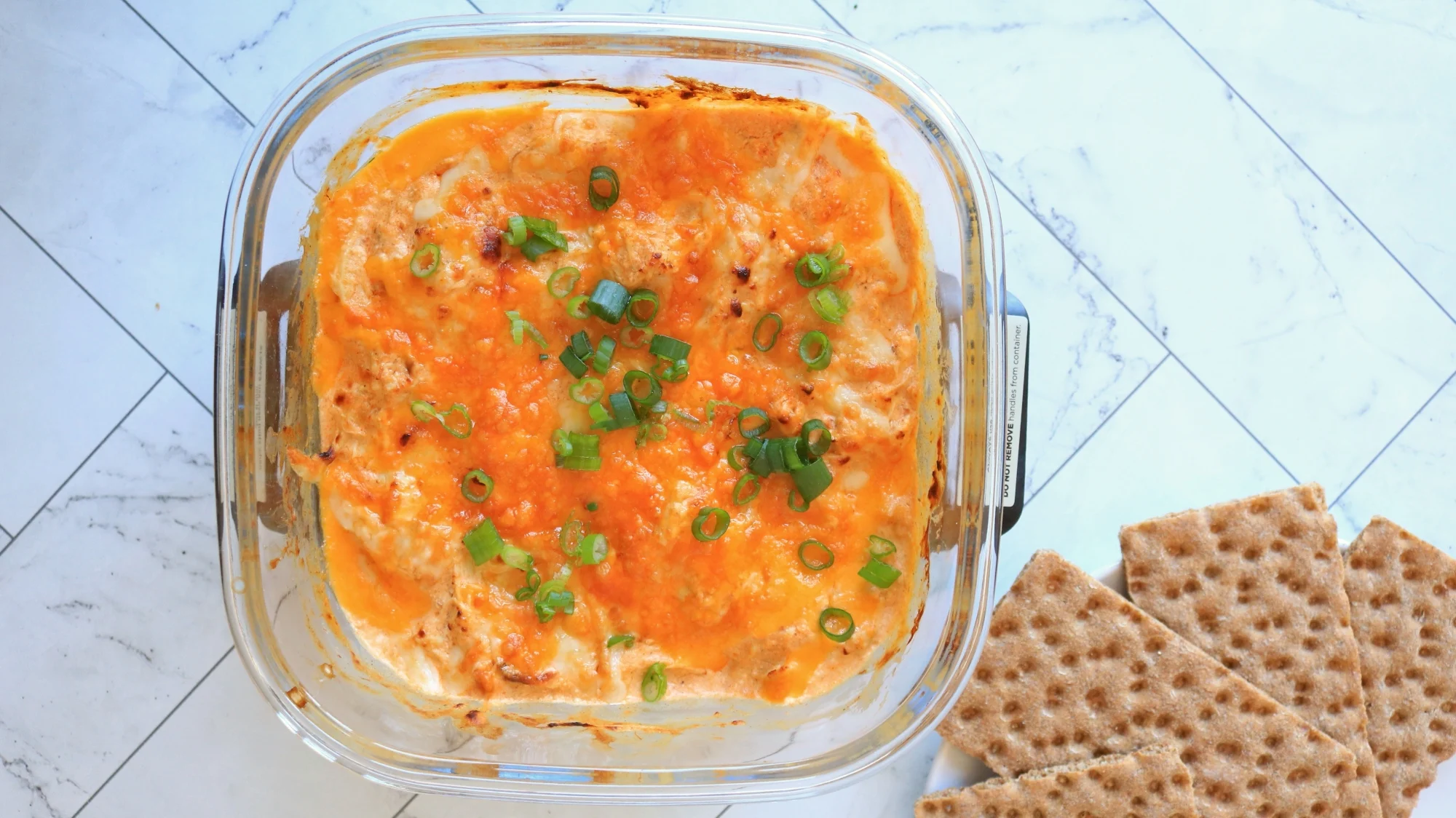 Buffalo chicken dip next to crisp breads.