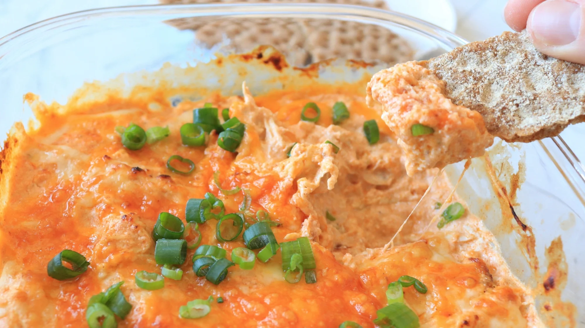 Buffalo chicken dip with a chip scooping a serving out.