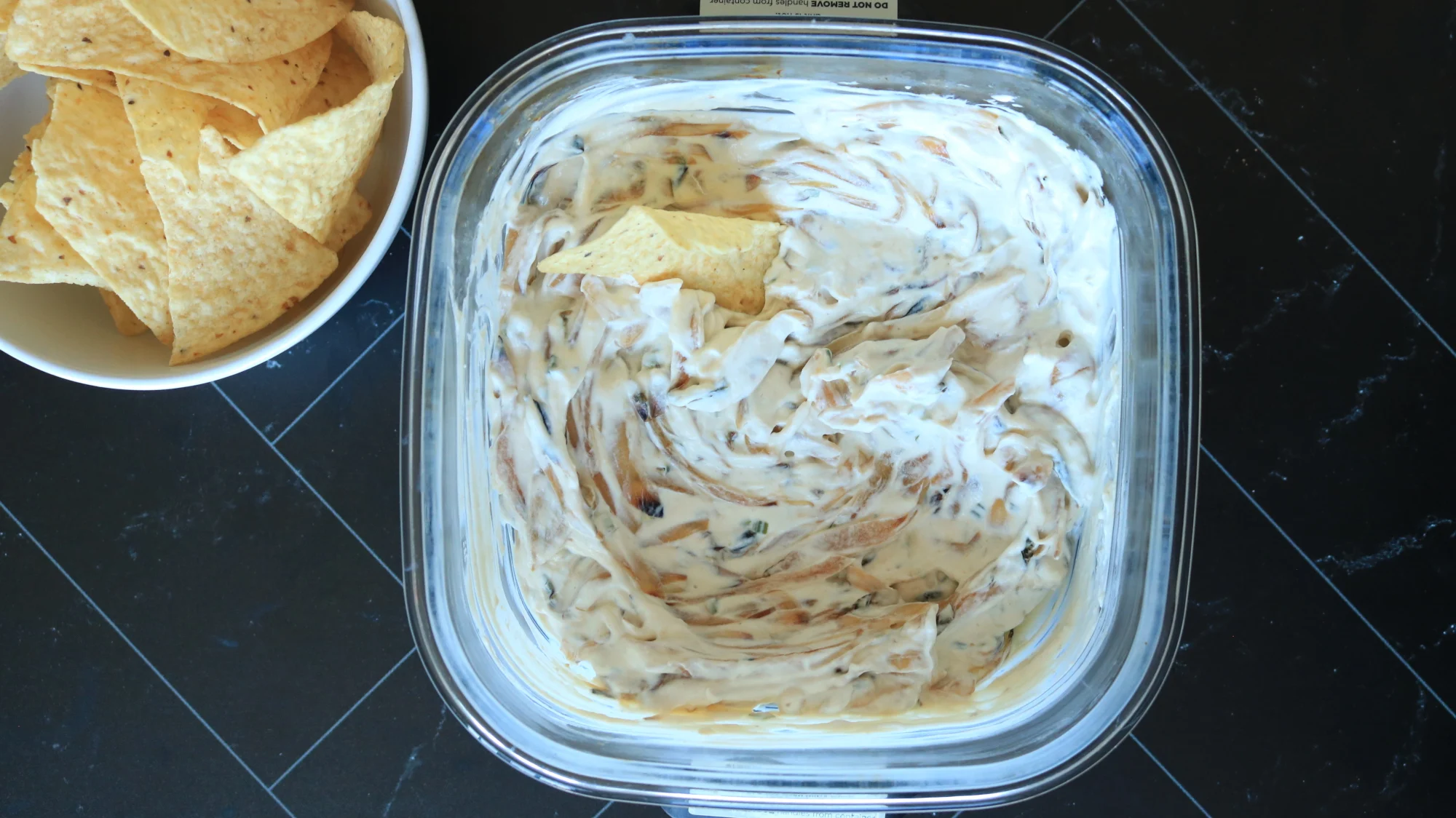 French onion dip next to a bowl of tortilla chips.