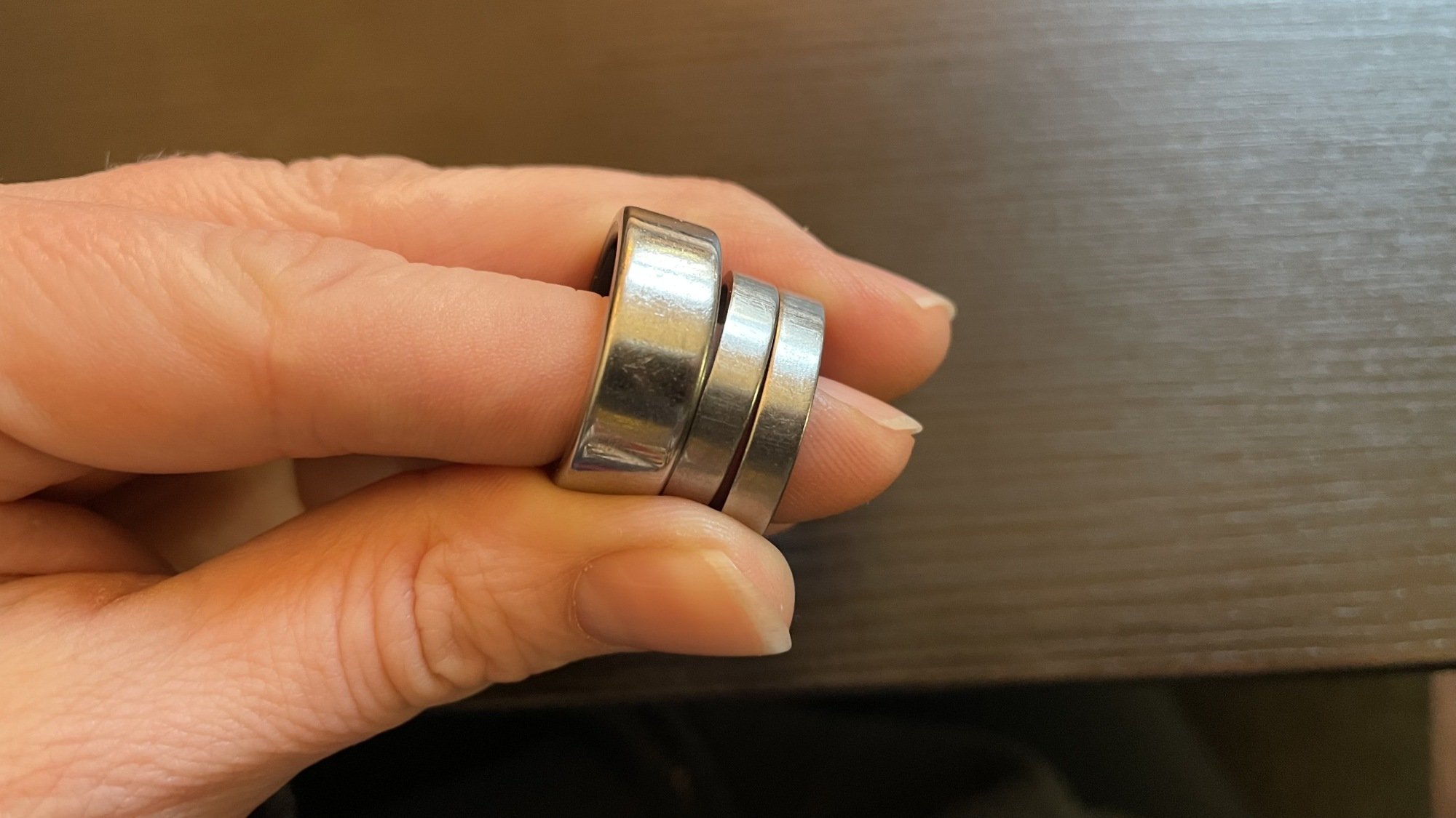 Three rings in hand: the Oura and two titanium rings. The Oura is more scratched.