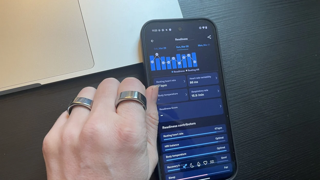 يد ترتدي خاتمي Oura بجوار تطبيق Oura