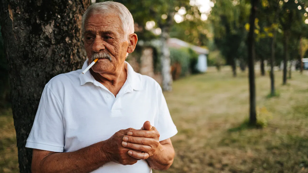 رجل مسن يدخن في الخارج