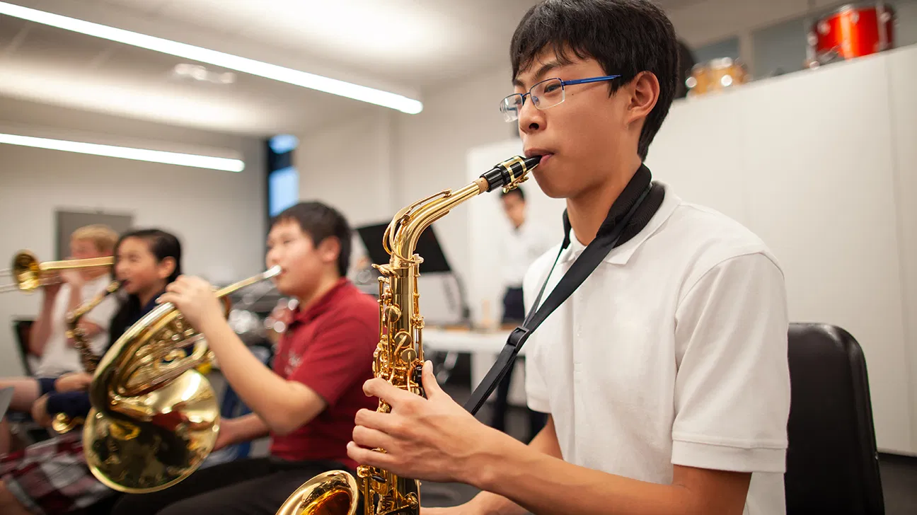 مراهق يعزف على الساكسفون في فصل الفرقة الموسيقية